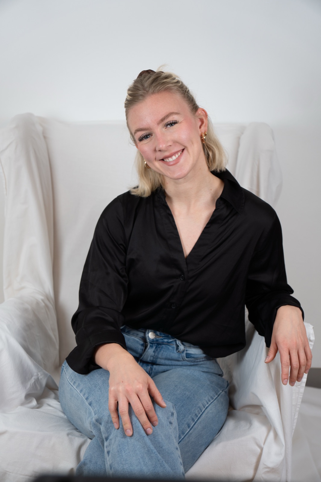 Luca Marie Schlieper lächelnd auf einem hellen Sessel